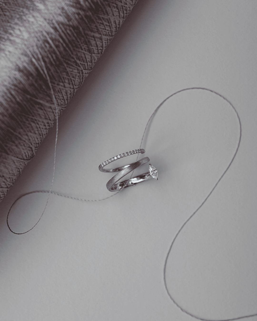 Silver-colored rings beside yarn, with parallel lines and open structures.