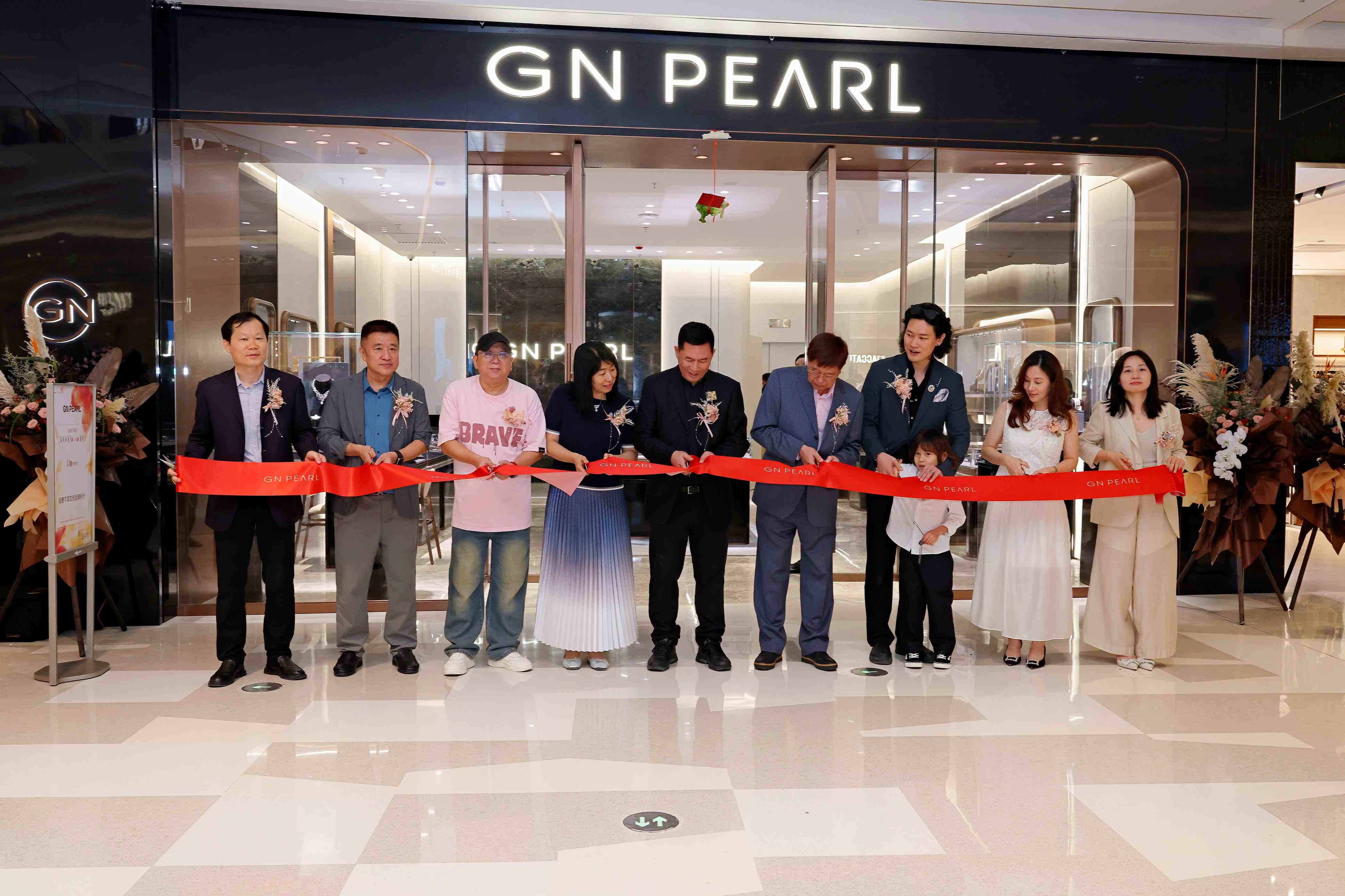 GN PEARL广州白鹅潭万象城门店开业剪彩,参与者在门头前手持红色丝带